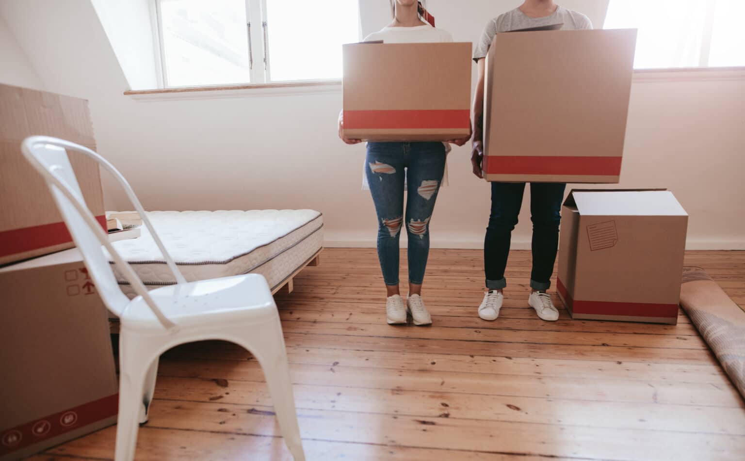 Cropped shot of young couple with big cardboard boxes moving to new place. Man and woman carrying big boxes and moving into new house.