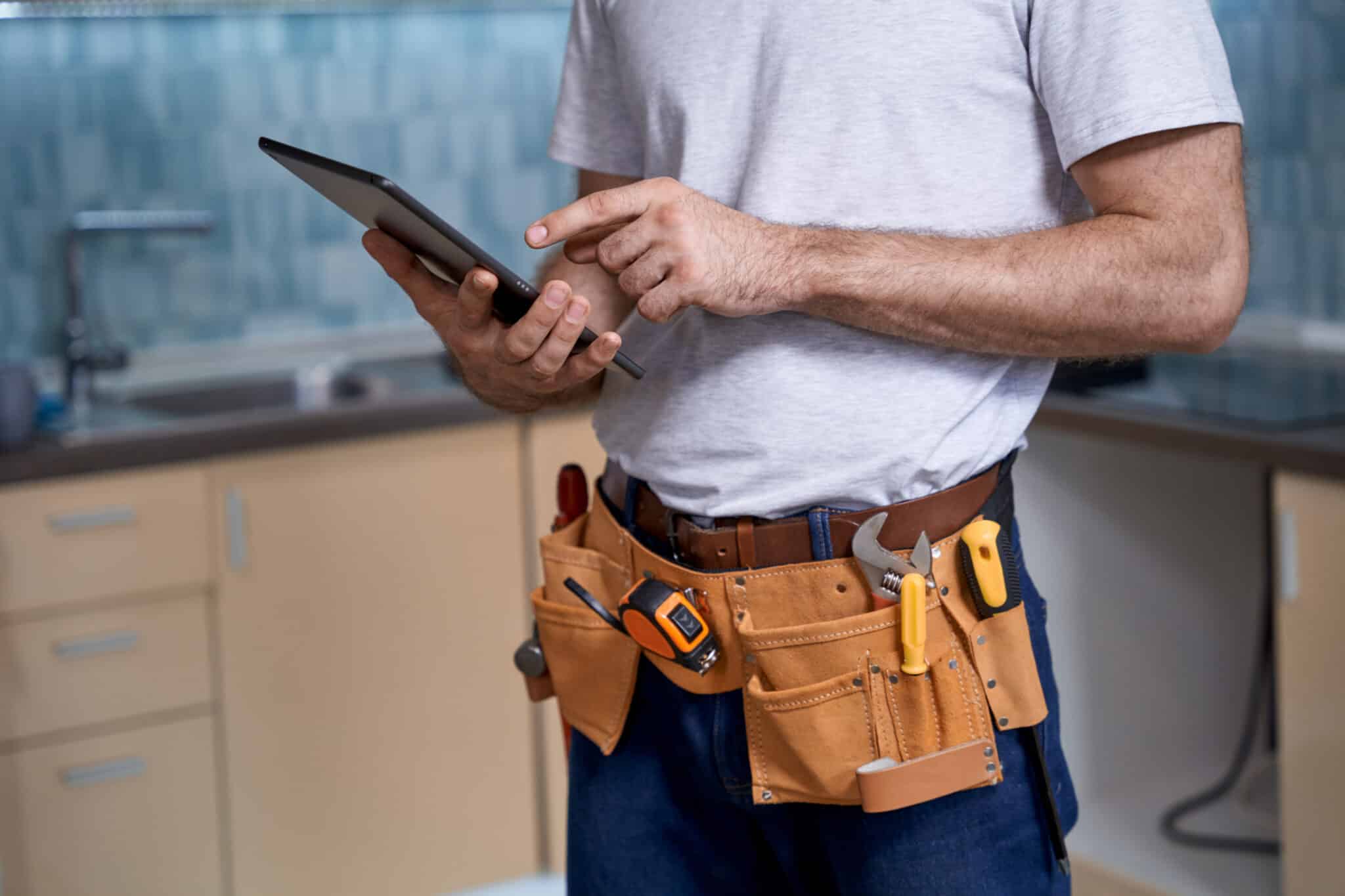 Young builder working with finger on digital tablet on kitchen background. Home master concept, construction and repair